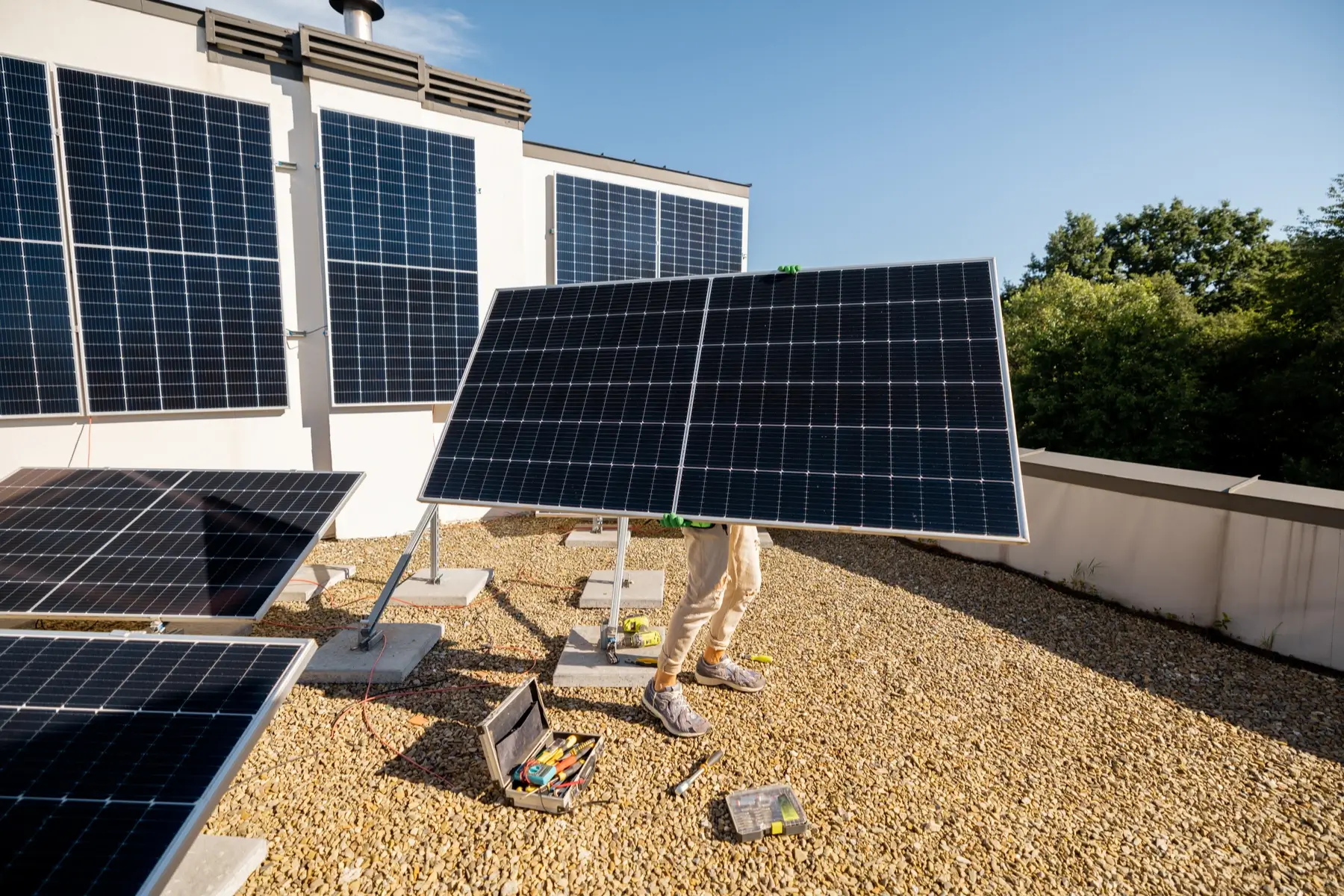 Handwerker trägt Solarmodul über Flachdach mit vorbereitetem Dachfensterbereich